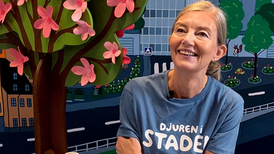 Sarah Sheppard, barnboksförfattaren ler mot en tecknad dekor.