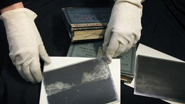 Hands hold an old glass negative